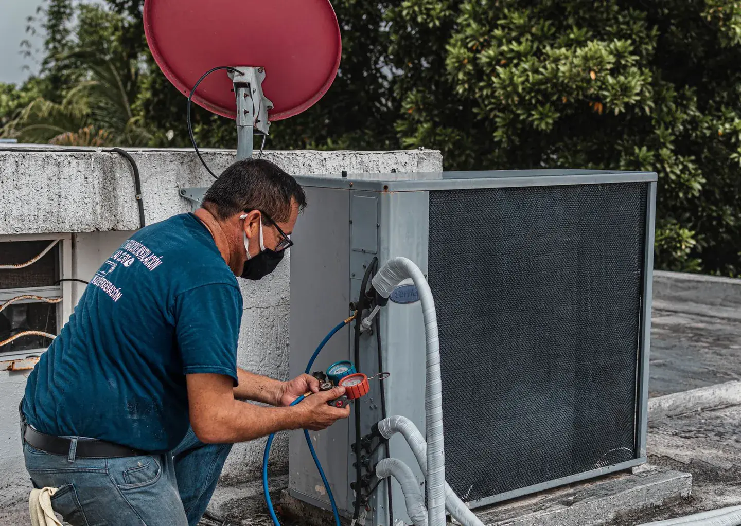 Technician checking an outdoor air conditioning unit with a set of refrigerant gauges